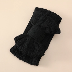 Close-up of black oversized bow headband for babies made of textured stretchy fabric