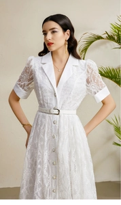 Détail d'une robe en dentelle blanche avec manches lanternes, col à revers et ceinture