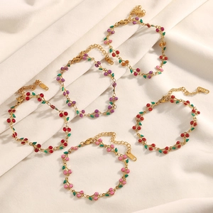 Détail de breloques cerise plaquées or 18K sur bracelets acier avec incrustation émail