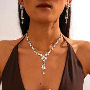 Detailed view of silver necklace and earrings set with zircons and tassel pendants