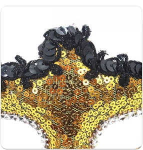 Macro shot of gold sequins and clear rhinestones on the edge of a masquerade mask