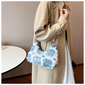 Detail of blue denim shoulder bag with white plush grid and acrylic chain strap