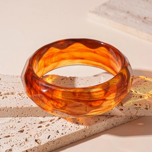 Detailed close-up of geometric faceted amber resin bangle on textured stone
