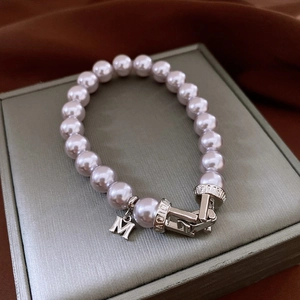 Gros plan du bracelet en perles avec pendentif M en argent et fermoir gravé élégant