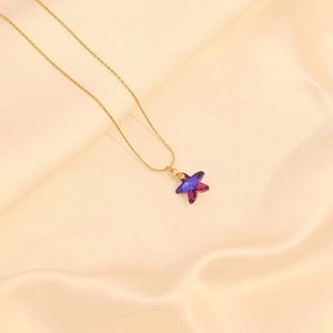 Gros plan d'un collier doré avec un pendentif en cristal étoile de mer dégradé bleu et violet