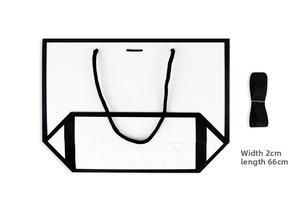 Detail of white gift bag with black woven handles and a 2cm wide black satin ribbon