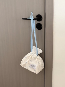 White fabric tissue storage bag with blue bow prints hanging on a modern door handle