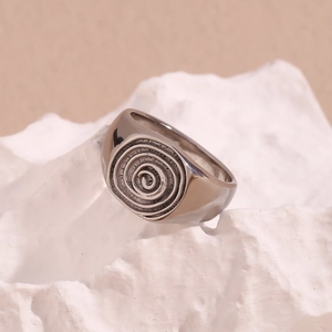 Detailed macro view of a silver signet ring with vintage spiral pattern on white stone