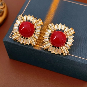 Detail of vintage gold earrings with red gems and sparkling zircons on a blue gift box