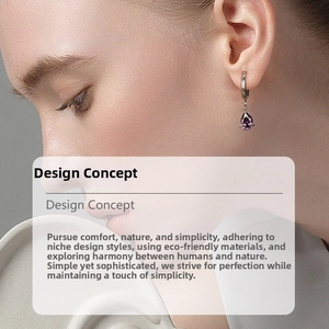Close-up of elegant gold hoop earrings with pear-cut purple zircon stone on a model