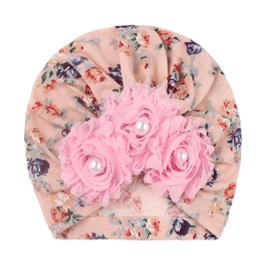 Detail of pink floral baby turban hat featuring fabric sunflowers with pearl centers