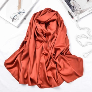 Detailed view of the burnt orange satin silk scarf with soft texture and magazine props