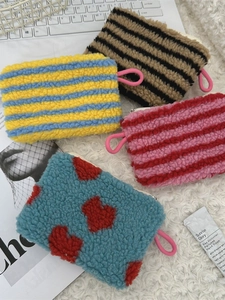 Colorful plush heart pouches with pink lanyards and zippers on white furry background
