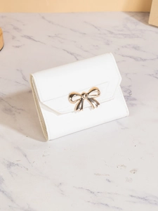 Detail of white tri-fold wallet with elegant gold bow clasp on marble surface