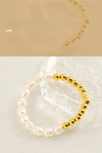Détail de perles baroques naturelles et billes dorées sur un bracelet en acier poli