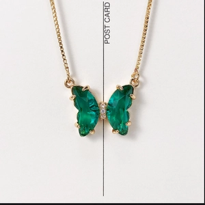 Macro shot of gold butterfly necklace with emerald green crystal wings and zirconia detail