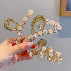 Detail of elegant camellia hair claw clip with cream pearls and floral resin accents