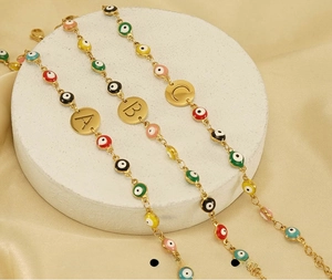 Detailed view of vacuum plated gold evil eye bracelets with hollow initial charms