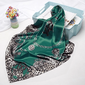 Detail of emerald green silk scarf featuring leopard print, chains, and baroque patterns