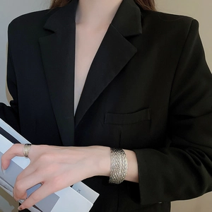 Close-up of multilayer layered metal bracelet and ring set with woven texture finish