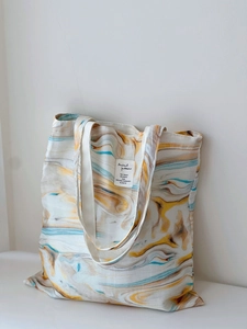 Detail of artistic canvas tote bag with abstract marble print and minimalist woven label