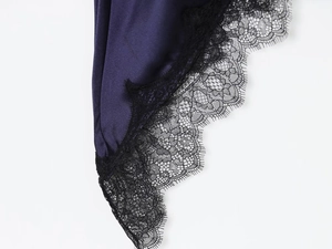 Gros plan sur le tissu en satin violet foncé avec détails délicats en dentelle noire