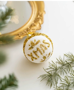 Detail of white Christmas ball with gold glitter XMAS lettering and beaded texture