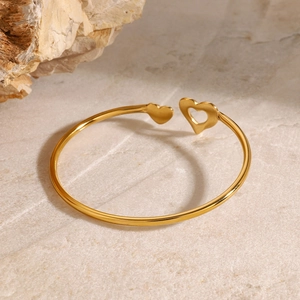 Elegant gold stainless steel open heart bangle bracelet on a marble background