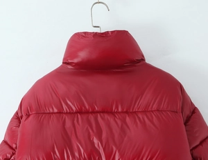 Detail view of red glossy puffer jacket with high stand collar and horizontal stitching