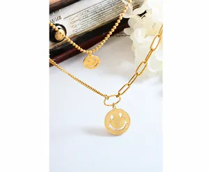 Detalle de collares dorados en capas con colgante de sonrisa Good Luck sobre radio retro