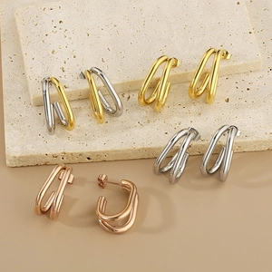 Détail montrant des boucles d'oreilles en U en or, argent et or rose sur un socle en pierre