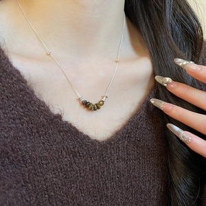 Tiger eye stone beaded round pendant necklace on silver chain worn over brown sweater