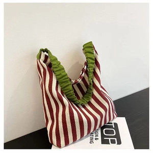 Close-up of red striped knit tote bag featuring a green scrunchie-style handle detail