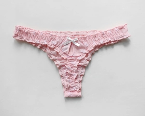 Detailed view of pink mesh thong featuring delicate lace ruffles and a white bow decoration