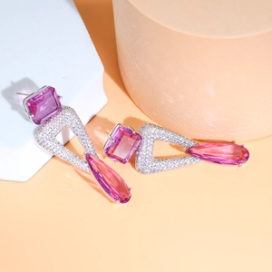 Macro shot of silver drop earrings with pink water-drop and geometric triangle stones