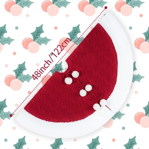 Detail of red cable knit Christmas tree skirt with white plush trim and pom poms