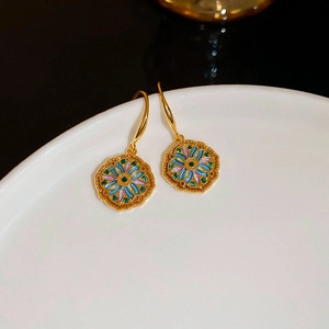 Detail view of vintage floral earrings with colorful enamel on a white ceramic plate