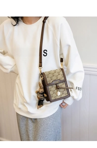 Detail showing embroidered bear canvas phone bag on model with cute hanging charm