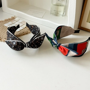 Detail of satin knotted headbands in paisley and geometric patterns with lifestyle props