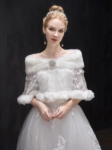 Close-up of bridal faux fur shawl with delicate lace and sparkling crystal brooch