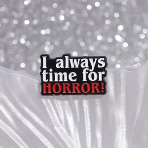 Gothic black enamel pin with I always time for HORROR text on a white textured background