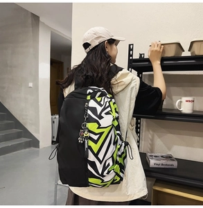 Side view of model wearing a graffiti print large capacity nylon backpack in tricolor