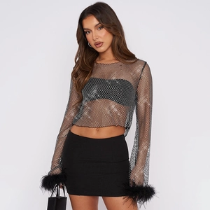 Détail d'un haut en maille transparente avec strass et poignets en plumes noires