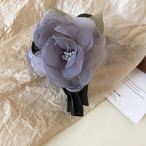 Détail d'une élégante pince à cheveux fleur en organza violet avec perle blanche au centre