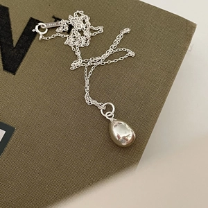 Minimalist 925 sterling silver necklace with water drop pendant on green textured fabric