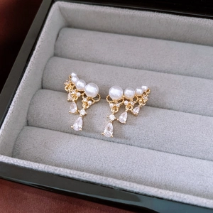 Macro shot of gold waterdrop pearl earrings with sparkling cubic zirconia in jewelry box