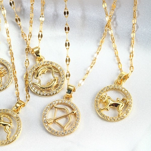 Detail of gold zodiac pendant necklaces with white zircon inlay on white silk fabric