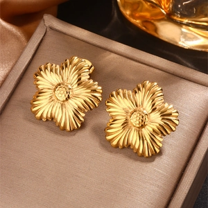 Makroaufnahme großer goldener Blumenohrringe mit radialen Petalen und strukturierter Mitte
