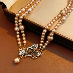 Detail of vintage double-layer champagne pearl necklace with crystal butterfly pendant
