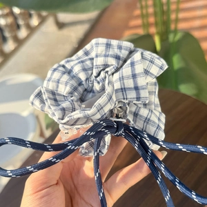 Detailed view of a blue and white checkered scrunchie with polka dot drawstring accent
